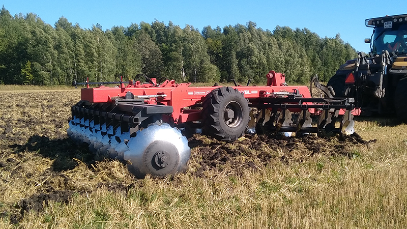 Disc harrow cutting through crop residue in a harvested grain field