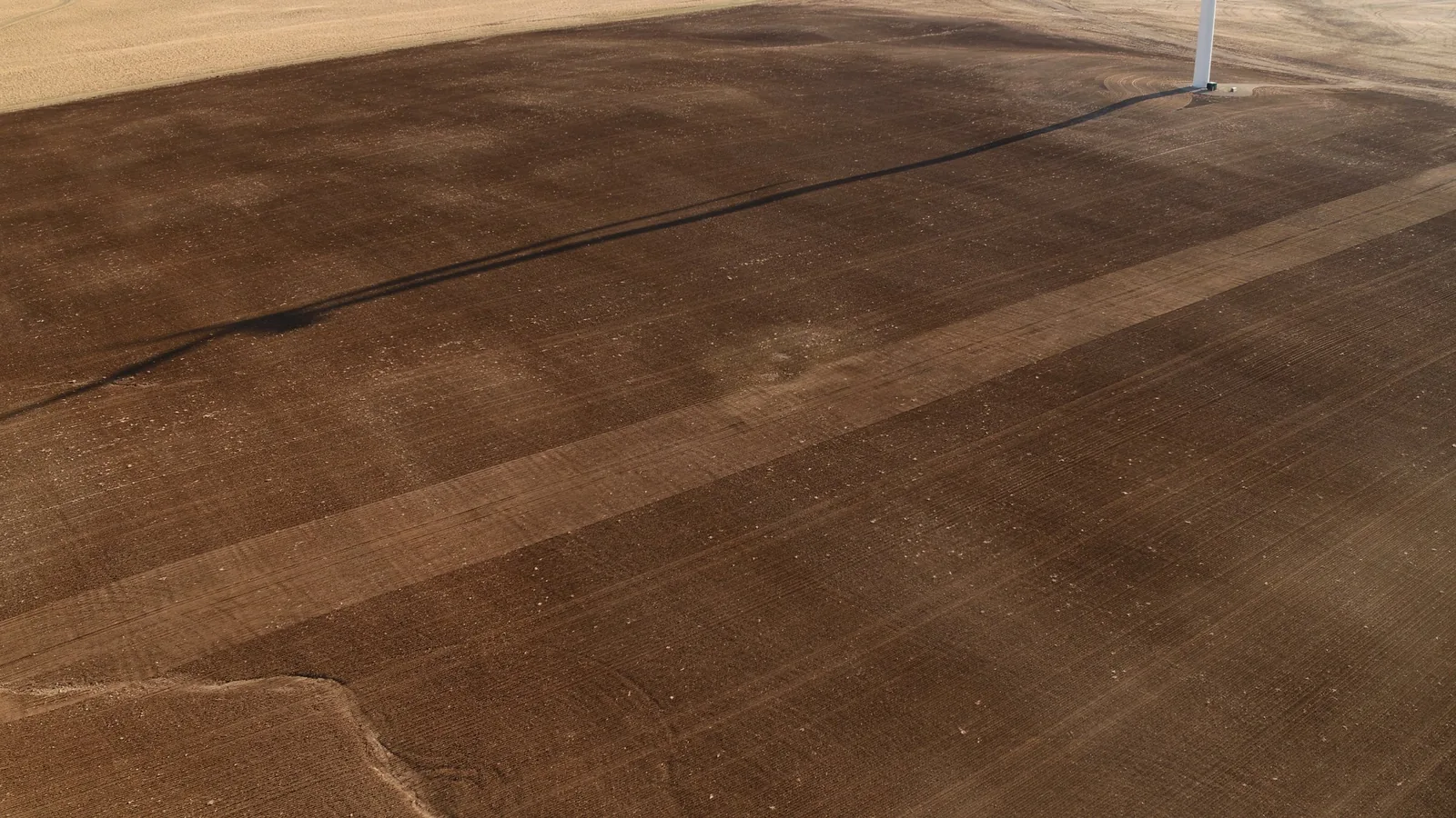Freshly tilled brown soil with visible tillage lines in prepared field