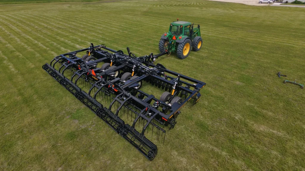 Green tractor pulling a Mandako Storm vertical tillage implement across a prepared field | Mandako Green tractor pulling a Mandako Storm vertical tillage implement across a prepared field
