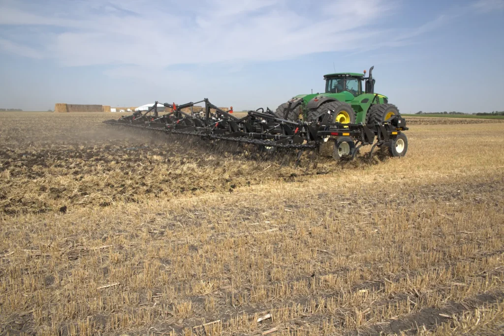 Green tractor pulling Mandako Chisel Flex across stubble field in autumn
