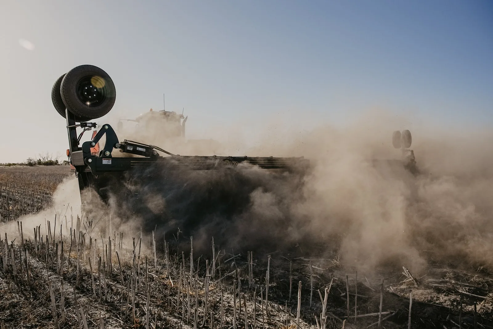 Mandako Cover Crop Crimper creating dust cloud while terminating cover crops in stubble field