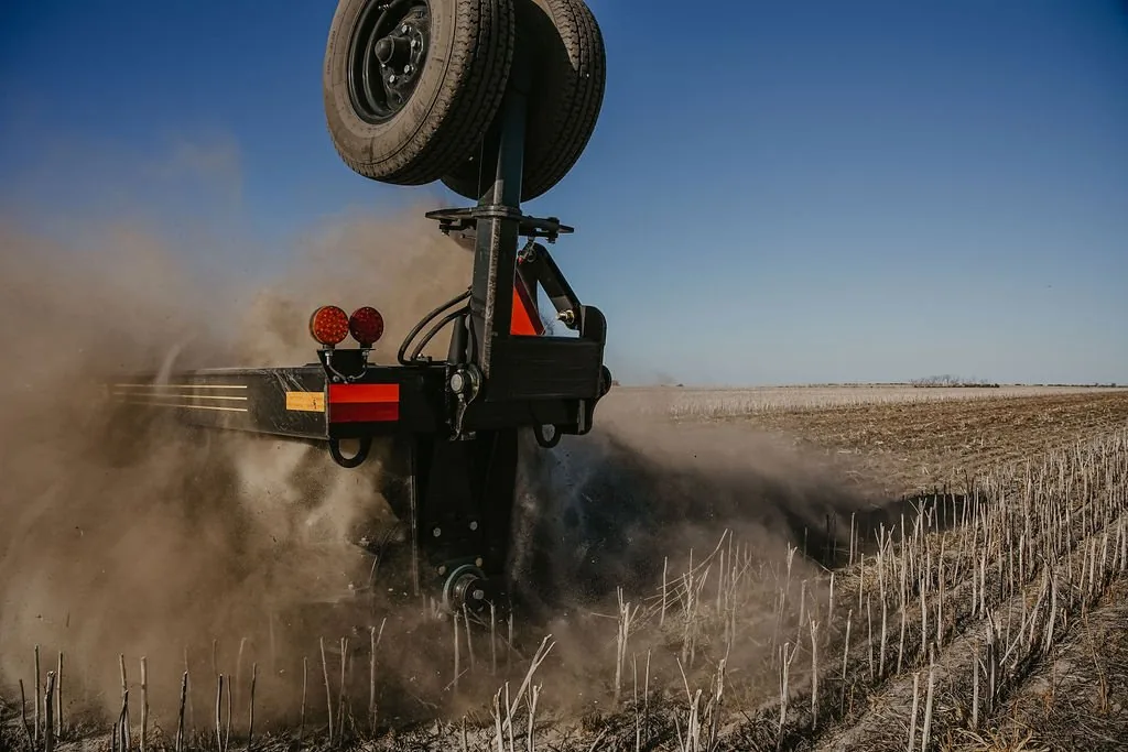 Mandako Cover Crop Crimper working through standing crop residue, creating dust clouds