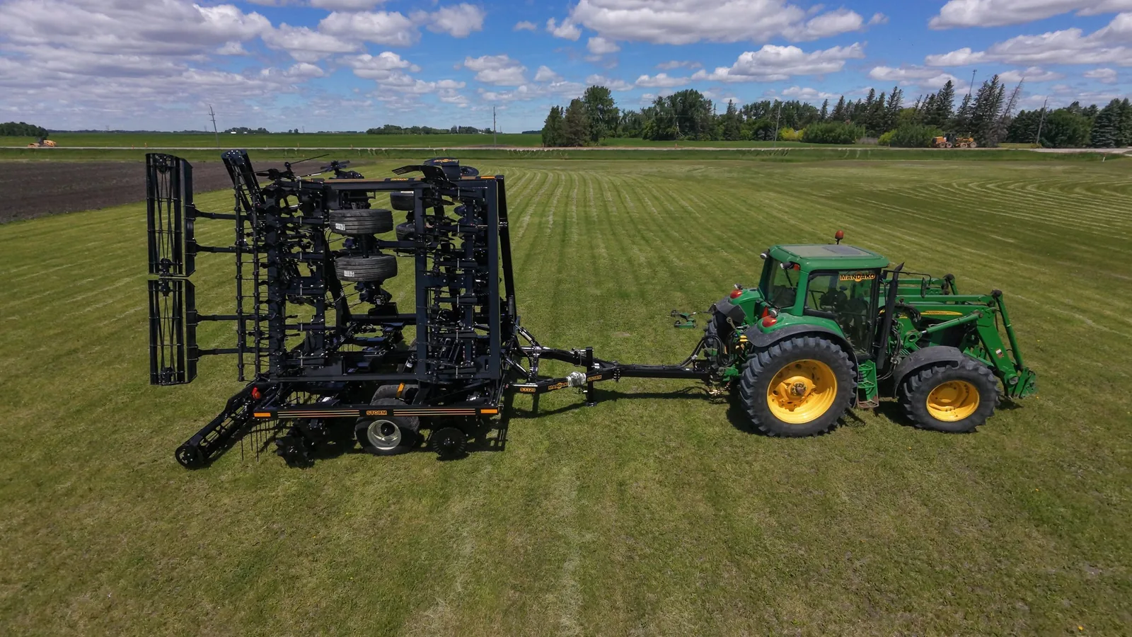 Mandako Storm vertical tillage implement towed by green tractor in grass field