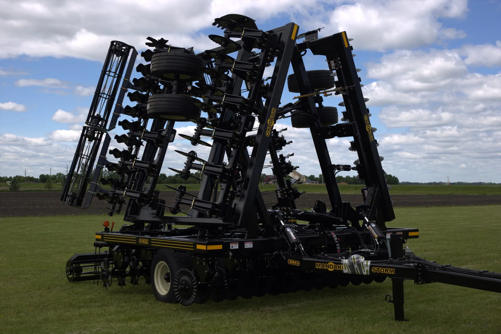 Mandako Storm vertical tillage tool in folded transport position on grass field