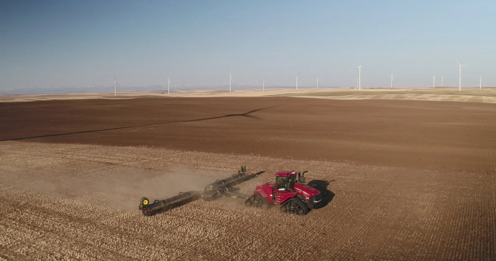 Red tractor with Mandako 3 PLEX LANDROLLER working stubble field from above