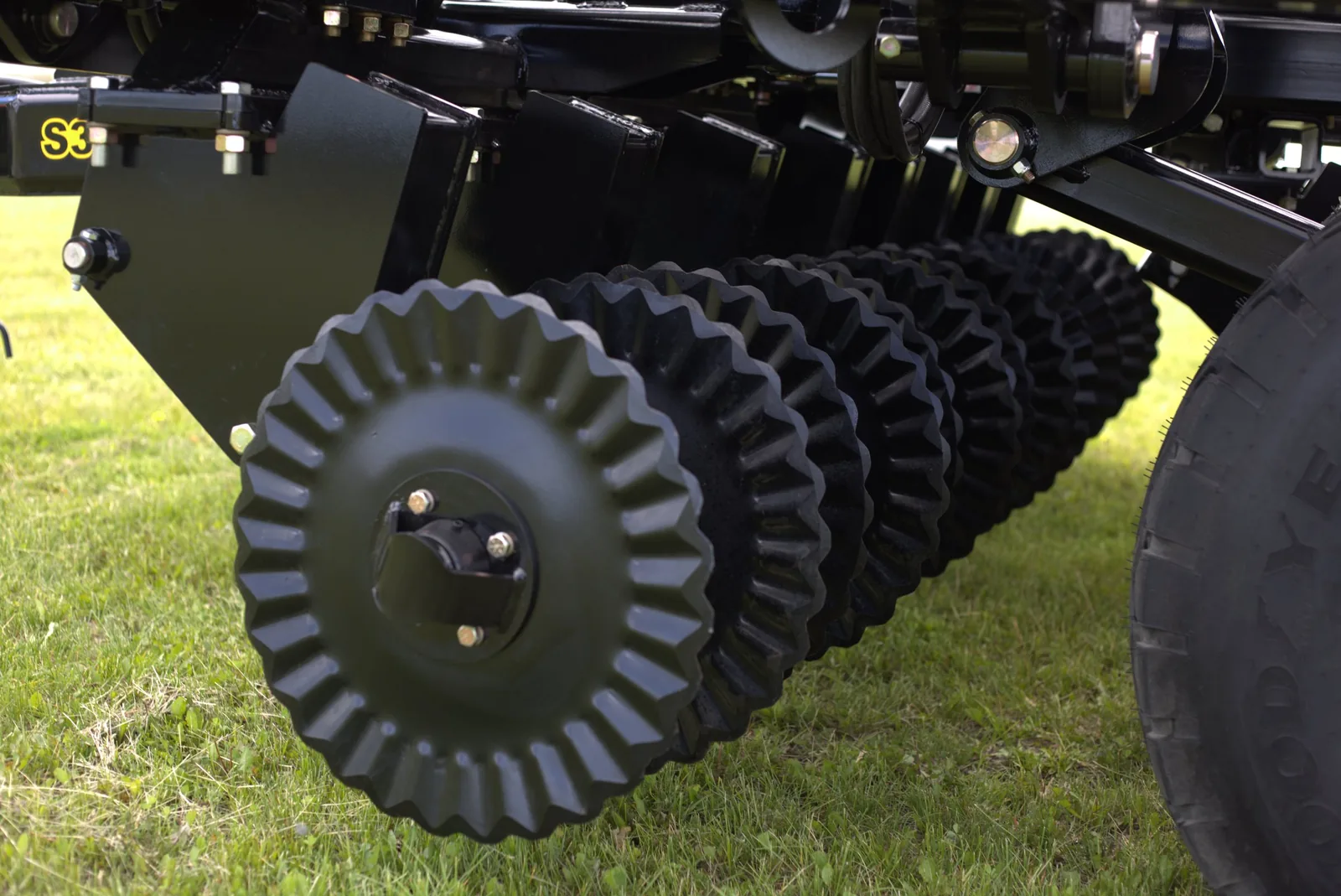 Row of ribbed compaction wheels on Mandako Storm implement, yellow frame visible
